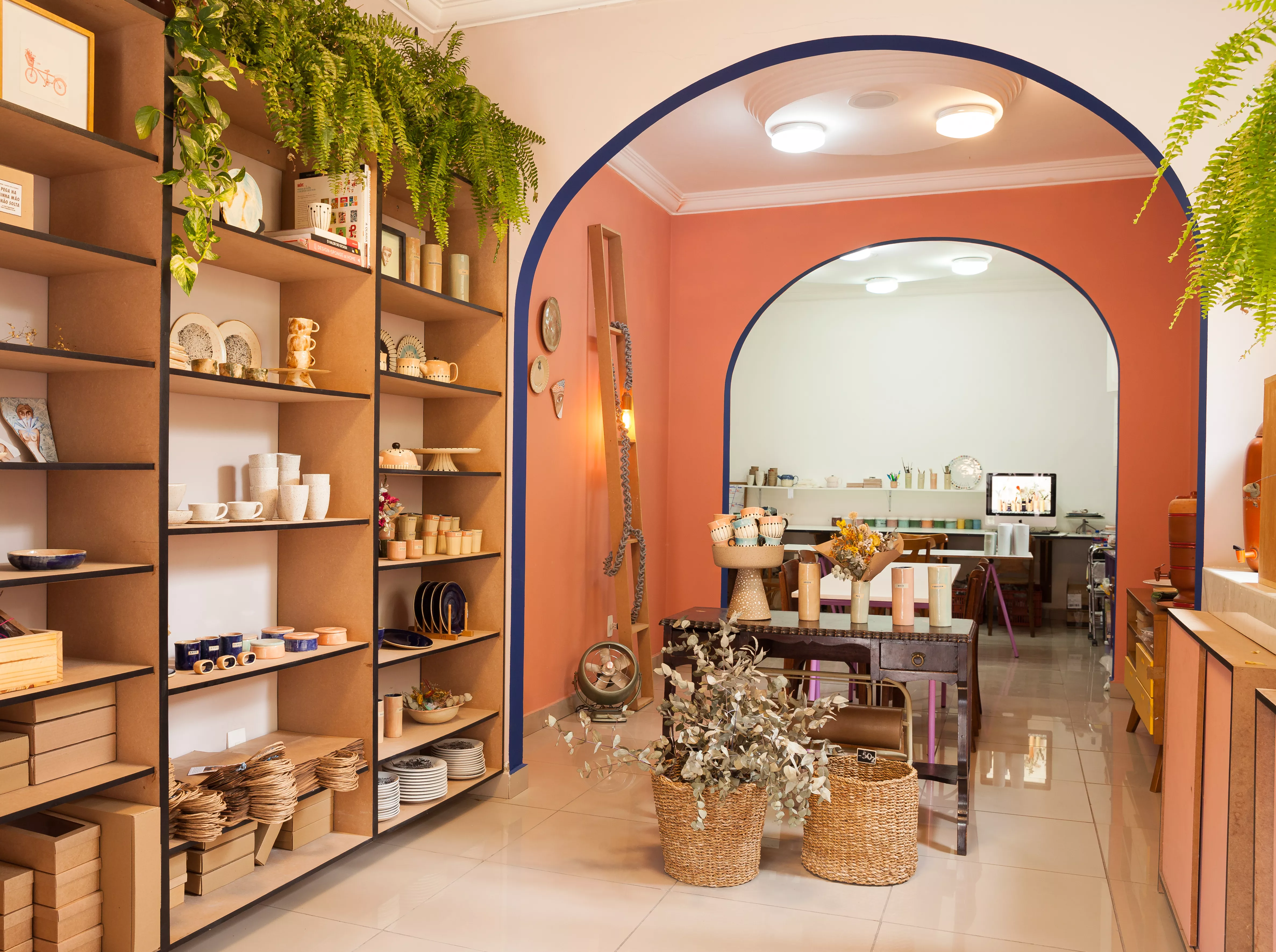 Interior da loja Atelier Thaís Mor. Lugar amplo com produtos expostos em mostruários e estantes.
