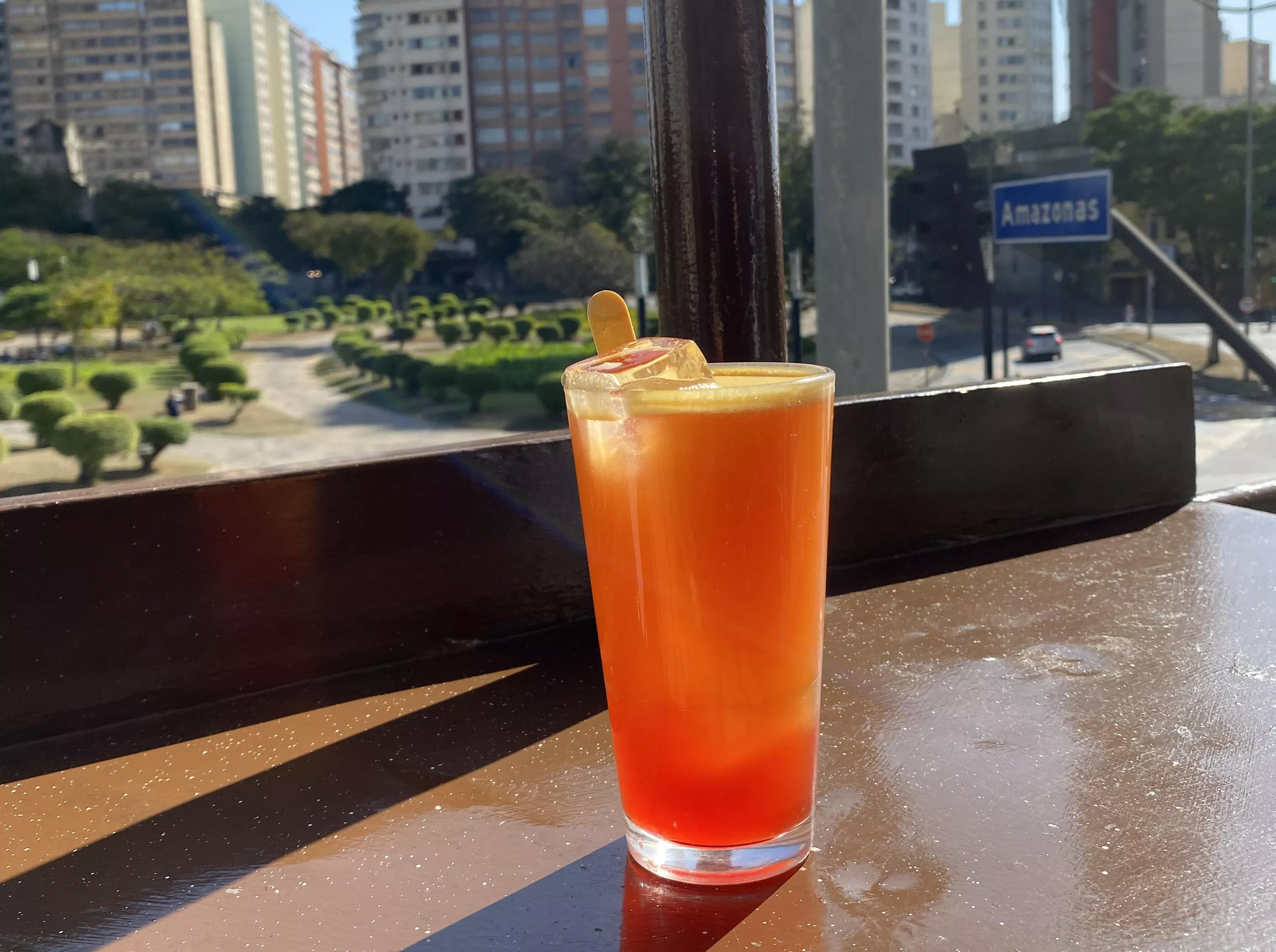 Imagem de bebida servida pelo Bar Palito com vista da cidade ao fundo.