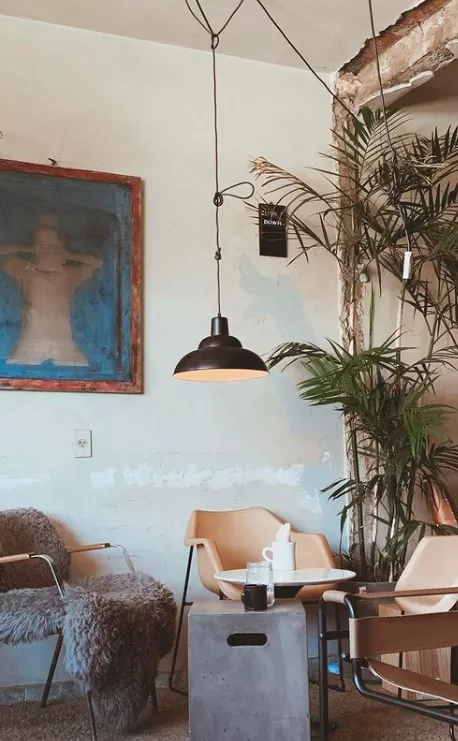 Interior do estabelecimento gastronômico Acervo Café. Ambiente amplo com mesa para clientes.