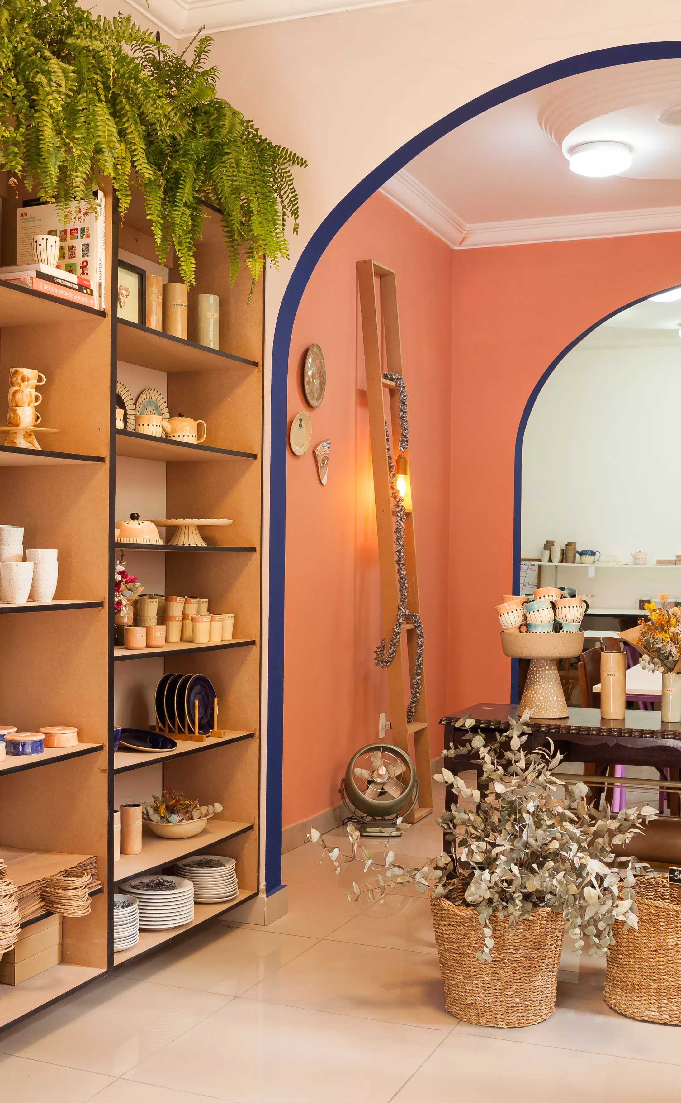 Interior da loja Atelier Thaís Mor. Lugar amplo com produtos expostos em mostruários e estantes.