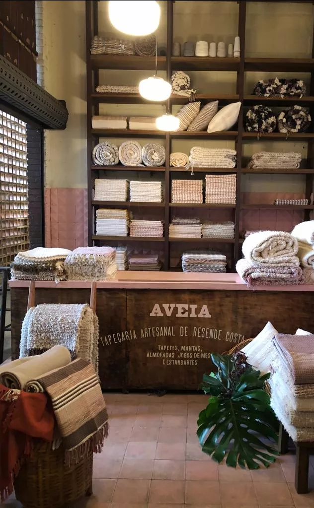 Interior da loja Aveia Tapeçaria. Lugar pequeno com produtos expostos em mostruários e estantes.