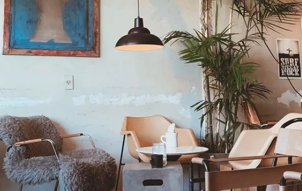 Interior do estabelecimento gastronômico Acervo Café. Ambiente amplo com mesa para clientes.