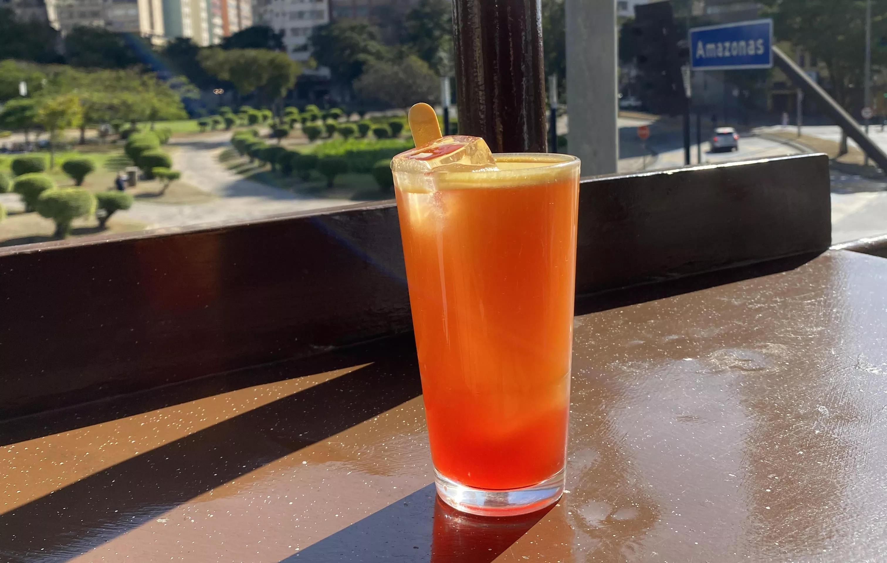 Imagem de bebida servida pelo Bar Palito com vista da cidade ao fundo.