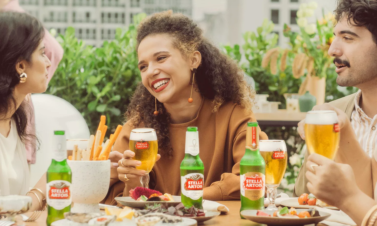Imagem de Pessoas Almoçando e uma Garrafa de Stella Artois ao Meio.